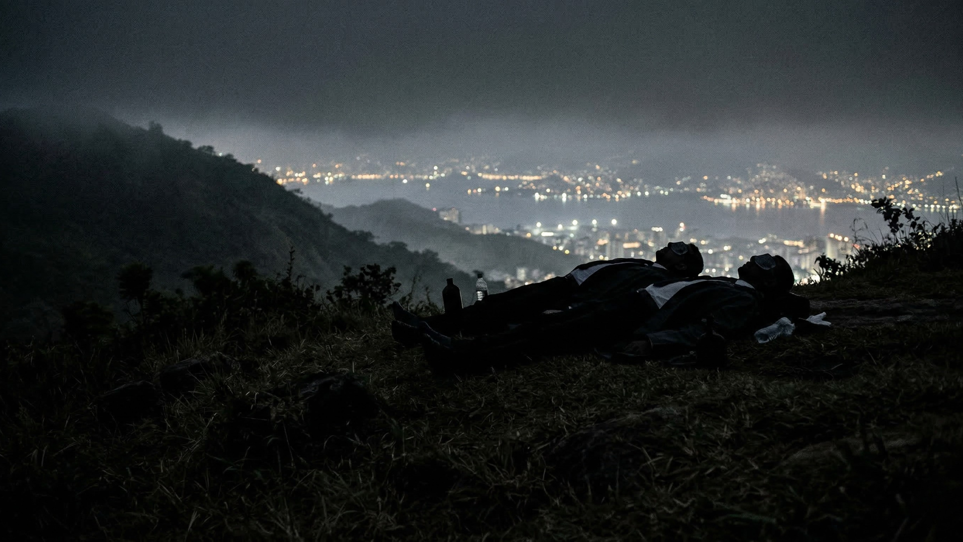 Two bodies on a hilltop overlooking Niteroi city lights at night